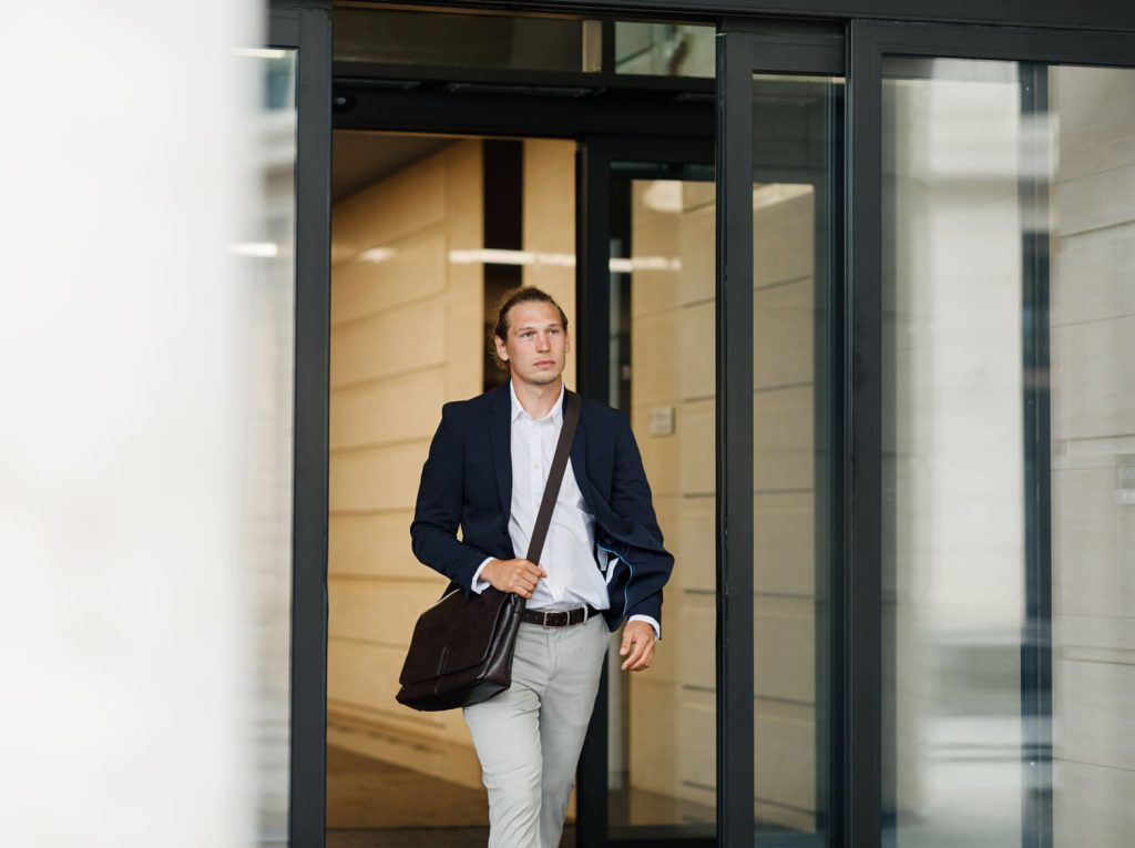Hombre de negocios caminando a través de puertas de vidrio en un edificio moderno.