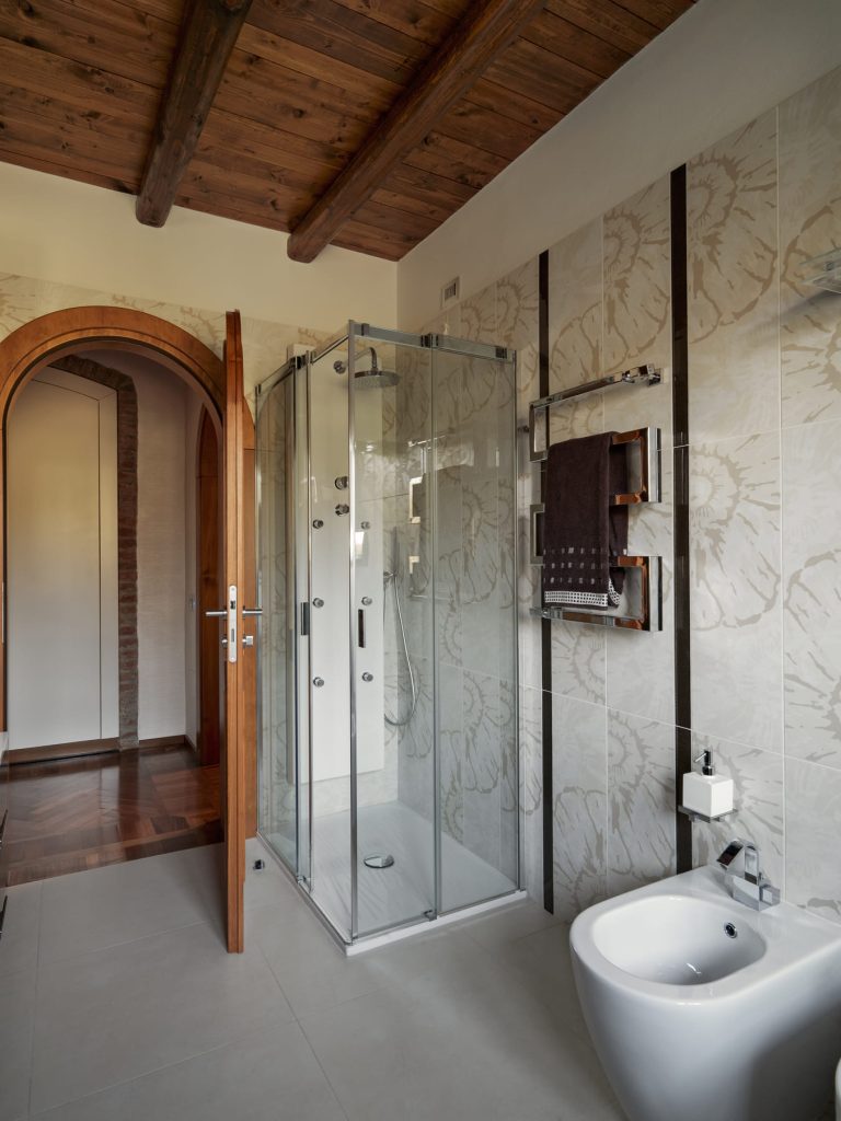 Baño elegante con cabina de ducha de vidrio y detalles en madera y mármol.